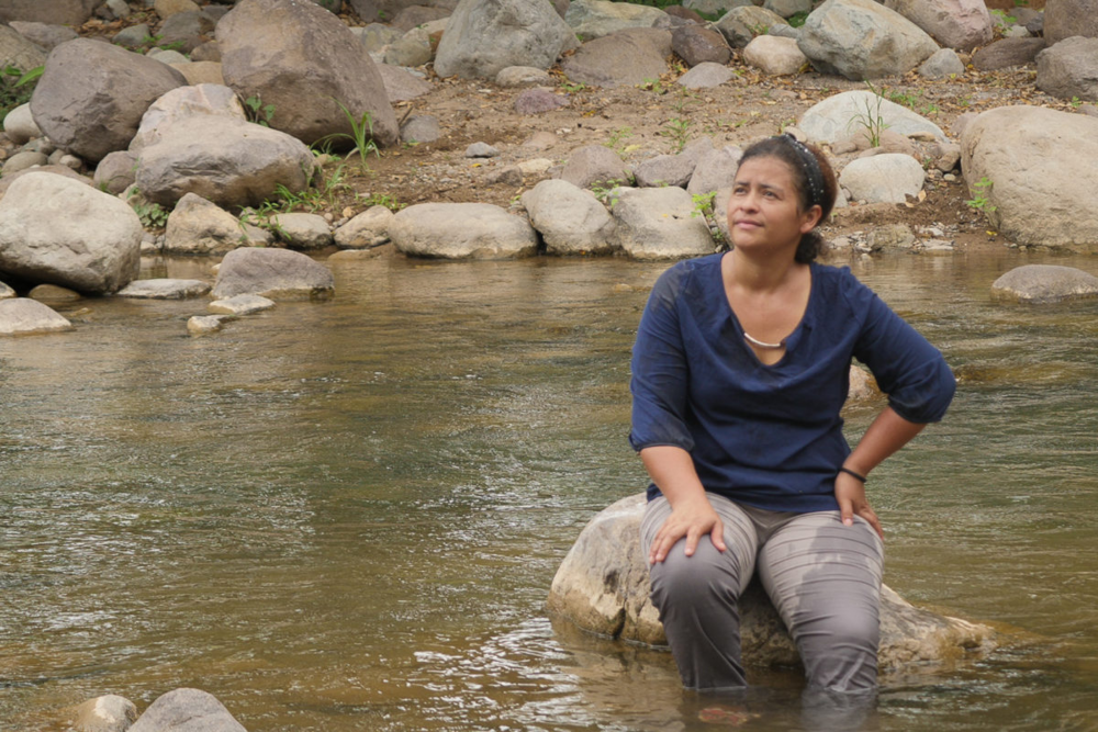Juana Zúniga se asienta en el río Guapinol, en el pueblo de Guapinol, ubicado en el valle del Bajo Aguán en el norte de Honduras, el 4 de julio de 2021. Juana Zúniga es miembro de la comunidad Guapinol y del Comité Municipal de Tocoa, Colón por la defensa de los recursos naturales. Crédito: Global Witness / María Aguilar / Iolany Pérez.