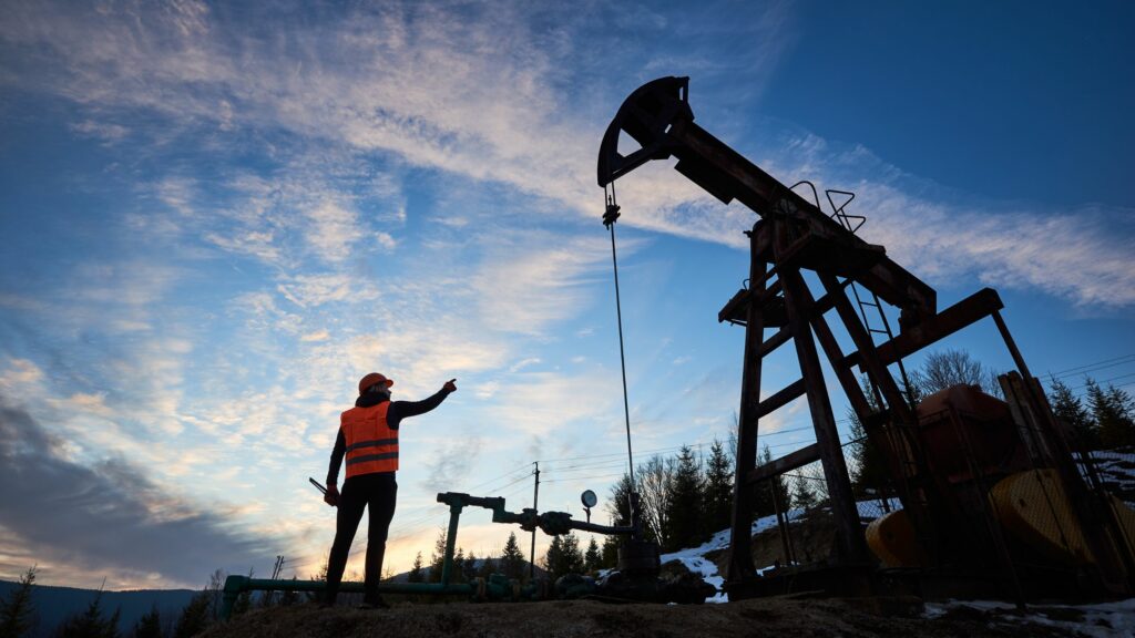 Operador petrolero apuntando al gato de la bomba del pozo de petróleo. Créditos: Anatoliy_gleb (Getty Images).