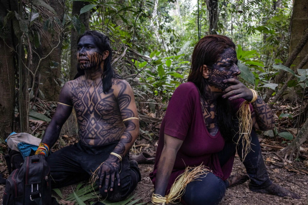 Xinã (izquierda) y Érica cubiertos con formas geométricas hechas con nane, pintura del árbol genip, que se dice que les permite ser ‘reconocidos’ por las serpientes. Su ritual de iniciación como chamanes comienza con ayahuasca y rapé de rome, y luego se limpian con oraciones. Créditos: Victor Moriyama / Dialogue earth