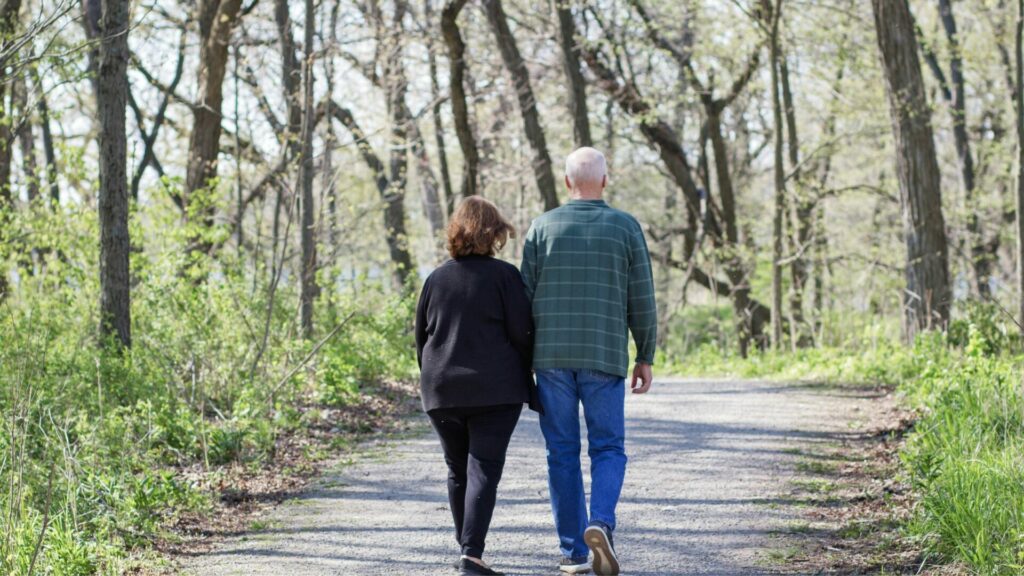 Pareja de la tercera edad caminando por un sendero en el bosque. Créditos: Karlamarie6.