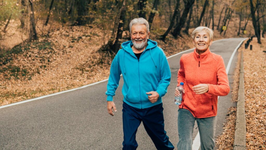 Pareja de la tercera edad corriendo por un sendero en el bosque. Créditos: Rgstudio.