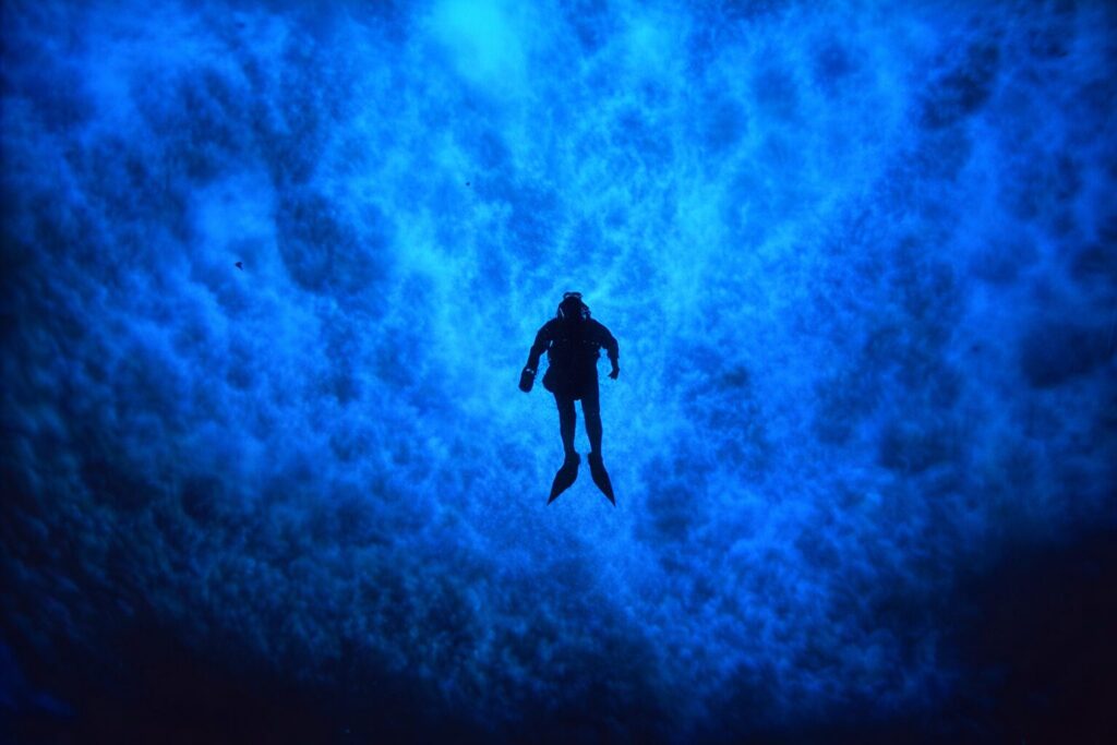 Paul Dayton, silueteado bajo el hielo marino, durante su proyecto de investigación sobre ecología bentónica. Cerca de la estación McMurdo, isla Ross, Antártida. Créditos: Regentes de la UC.