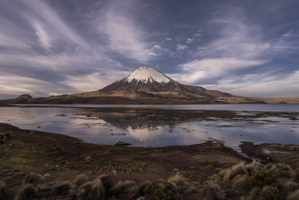El volcán Parinacota, un imponente estratovolcán de casi 6.350 metros de altura, se alza en la frontera entre Chile y Bolivia, dentro del Parque Nacional Lauca. Su cumbre nevada, sus laderas cubiertas de pajonales altoandinos y su simetría casi perfecta. Créditos Tamara Merino/UNESCO