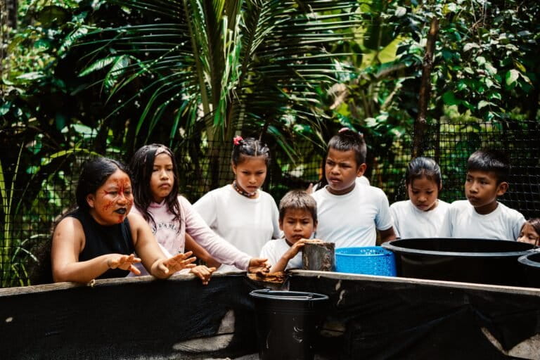 Janeth Piaguaje explica el cuidado de las tortugas en el arenario con niñas y niños de la Escuela Ëkowari. Créditos: cortesía CI Ecuador
