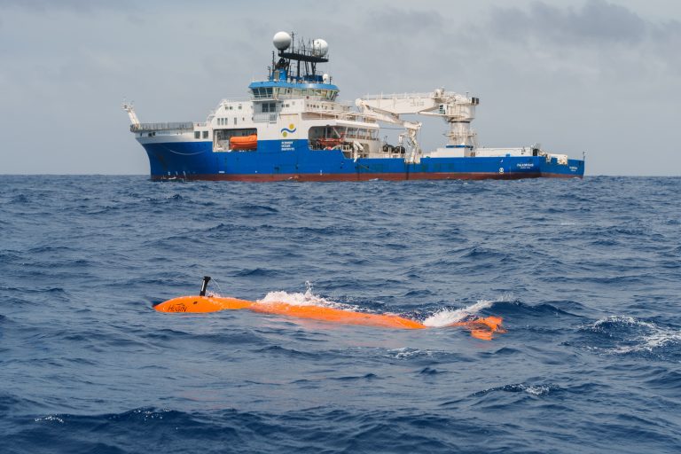 El vehículo submarino autónomo (AUV) The Childlike Empress navega junto al buque de investigación Falkor (too) antes de sumergirse miles de metros bajo la superficie del océano para realizar una misión cartográfica. El equipo científico utilizó el sonar instalado a bordo del buque para cartografiar la región y después empleó el AUV The Childlike Empress para generar mapas de alta resolución y recopilar datos ambientales en el área de interés. Estos mapas permitieron determinar las coordenadas precisas para desplegar el SuBastian, lo que condujo al descubrimiento, en un tiempo récord, de dos nuevos campos hidrotermales activos. Créditos: Alex Ingle, Schmidt Ocean Institute.