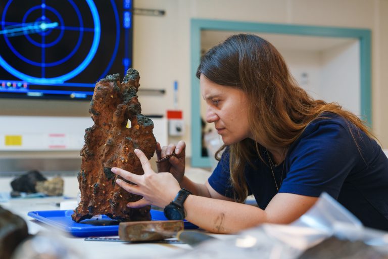 La Dra. Olivia Soares Pereira, del Monterey Bay Aquarium Research Institute, retira cuidadosamente muestras biológicas de la punta de una chimenea hidrotermal recuperada en un sitio recién descubierto. El equipo científico utiliza el vehículo operado remotamente SuBastian para obtener muestras geológicas, biológicas y de agua, además de lecturas de sensores y testigos de sedimento obtenidos por empuje a grandes profundidades. Las muestras se analizan en los laboratorios del buque. Créditos: Alex Ingle, Schmidt Ocean Institute.